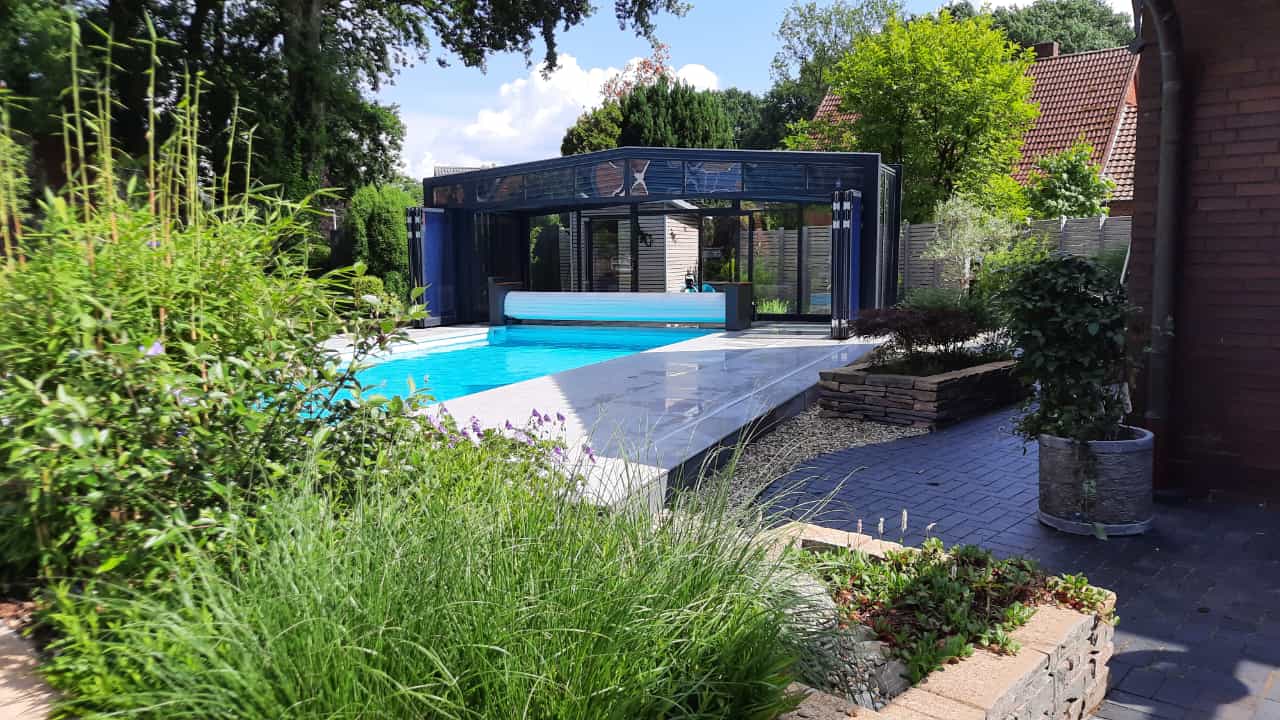 Ein moderner Pool mit einer blauen Überdachung und umliegender Gartenlandschaft.